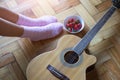 On the parquet floor - guitar, a ÃÂup of strawberries and female feet in pink socks.